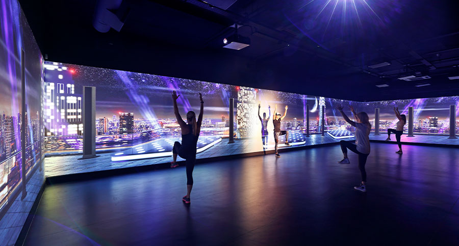 Friends working out together in a home gym that uses integrated virtual systems to provide an immersive experience.